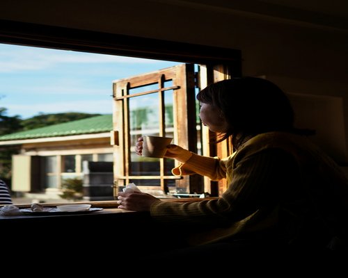 Persona desayunando cerca de la ventana con luz de mañana
